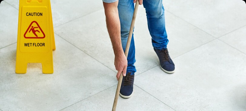 Person mopping floor with wet floor sign